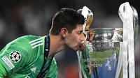 Kiper Real Madrid, Thibaut Courtois mencium trofi Liga Champions saat upacara penyerahan medali setelah Real Madrid keluar sebagai pemenang di laga final melawan Liverpool yang berlangsung di Stade de France, Saint Denis, Sabtu, 28 Mei 2022 waktu setempat. (AFP/Paul Ellis)
