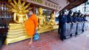 Seorang biksu Buddha berjalan melewati polisi antihuru-hara dekat tempat KTT APEC di Bangkok, Thailand, Jumat (18/11/2022). KTT APEC yang berlangsung pada tanggal 18-19 November 2022 diwarnai aksi unjuk rasa. (AP Photo/Sarot Meksophawannakul)