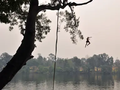 Seorang bocah lelaki melompat ke sungai Penrith saat gelombang panas di Sydney, Kamis (19/12/2019). Pekan ini Australia mengalami rekor hari terpanasnya yang tercatat dalam sejarah dan gelombang panas diperkirakan akan terus meningkat. (Farooq KHAN/AFP)