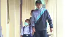 Seorang pria mengantar murid untuk mengikuti kegiatan belajar di SD Negeri Rendang, Karangasem, Bali, Rabu (29/11). Meskipun status Gunung Agung sudah menjadi awas, para siswa tetap masuk sekolah dengan mengenakan masker. (Liputan6.com/Andi Jatmiko)