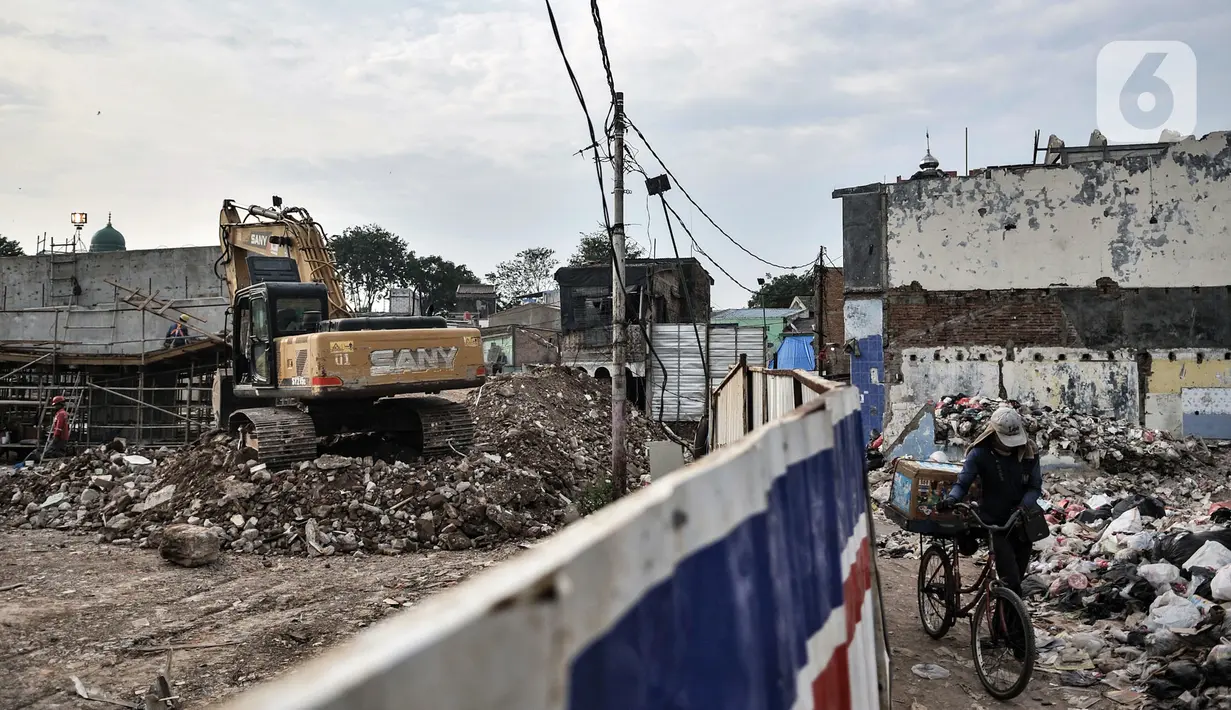 Pedagang asongan melintas dekat proyek pembangunan Tol Becakayu seksi 1A di kawasan Pasar Gembrong, Jakarta, Selasa (14/7/2020). Proyek pembangunan Tol Becakayu seksi 1A rute Kampung Melayu-Cipinang Muara sepanjang 3,5 kilometer tersebut molor dari target. (merdeka.com/Iqbal S. Nugroho)
