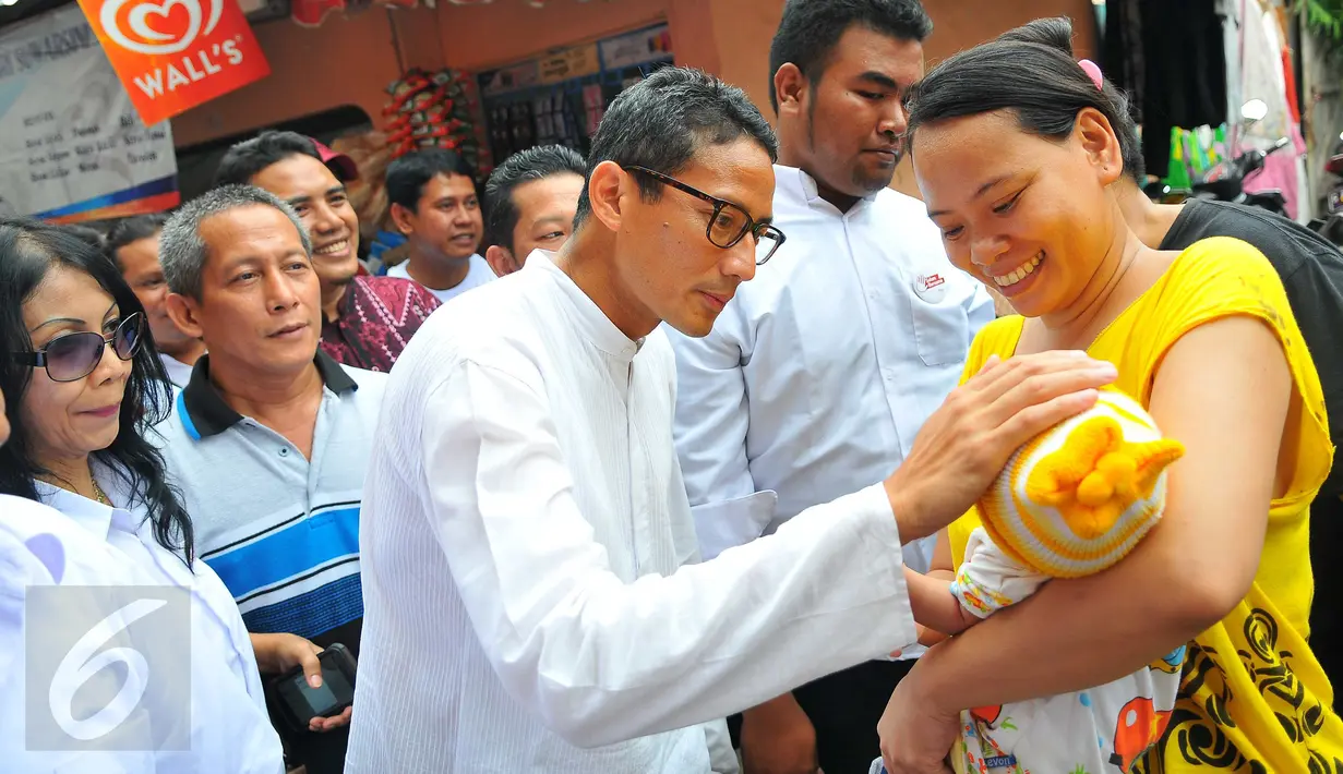 Cawagub DKI Jakarta, Sandiaga Uno menyapa seorang bayi yang digendong ibunya saat mengunjungi kawasan Tendean, Jakarta, Sabtu (5/11). Di kawasan itu, Sandiaga berjanji akan memberdayakan ibu-ibu melalui pembukaan lapangan kerja (Liputan6.com/Angga Yuniar)