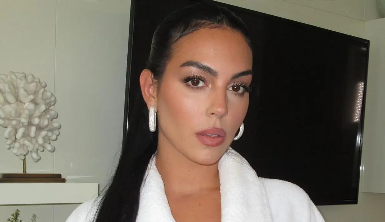 Wajahnya dipoles makeup glam dengan eyeshadow coklat dan kontur yang tegas. Sementara rambutnya ditata bergaya sleek half up. [Foto: IG/georginagio].