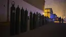Para wanita berjalan melewati barisan tabung oksigen kosong saat orang-orang menunggu toko buka untuk mengisi tabung mereka di Villa El Salvador, Lima, Peru, Selasa (6/4/2021). Warga Peru terus berjuang mendapatkan oksigen medis untuk merawat pasien COVID-19. (AP Photo/Rodrigo Abd)