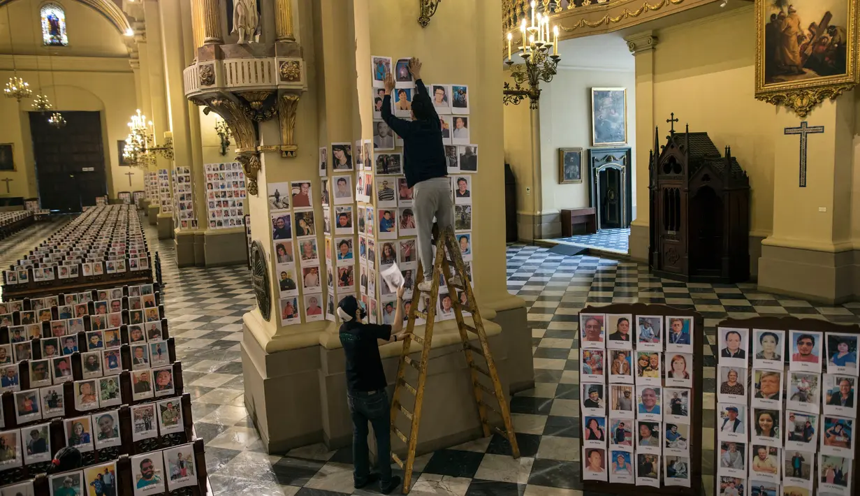 Pekerja menempelkan potret korban meninggal akibat virus corona di dalam Katedral, di Lima, Peru pada 13 Juni 2020. Misa Minggu di Katedral Lima dihadiri lebih dari 4.000 potret mereka yang telah meninggal dalam pandemi Covid-19 yang menyebar di Peru. (AP Photo/Rodrigo Abd)