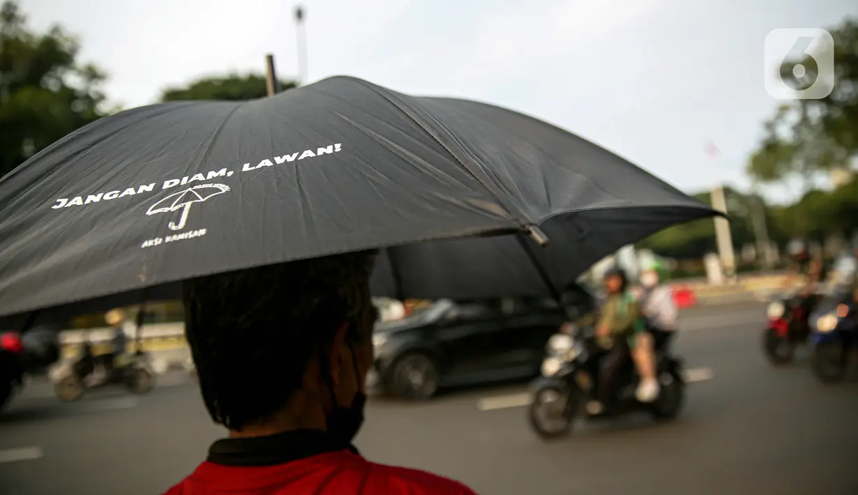 Anggota Jaringan Solidaritas Korban untuk Keadilan (JSKK) menggunakan payung hitam bertuliskan "Jangan Diam, Lawan!" saat melakukan Aksi Kamisan ke-795 di seberang Istana Merdeka, Jakarta, Kamis (16/11/2023). (Liputan6.com/Faizal Fanani)