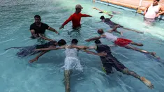 Anak muda Palestina yang diamputasi berlatih di bawah instruksi Majdi al-Tatar (kiri)  di kolam renang Kota Gaza (30/7/2019). Tatar, yang kehilangan kaki kanannya akibat kecelakaan pada masa kecilnya, melatih warga Palestina yang diamputasi selama konflik dengan Israel. (AFP Photo/Mahmud Hams)