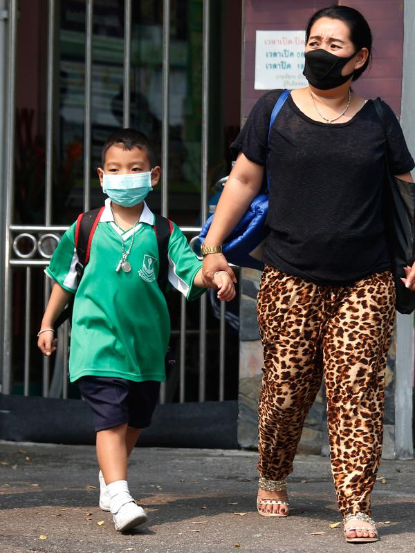 Seorang anak laki-laki mengenakan masker saat dijemput orang tuanya di Bangkok, Thailand (30/1). Pihak berwenang tengah berjuang untuk mengelola krisis polusi yang telah menimbulkan kekhawatiran. (AP Photo/Sakchai Lalit)