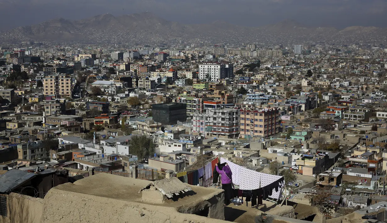 Seorang wanita menjemur pakaiannya di atap yang menghadap kota Kabul di Kabul, Afghanistan (28/11/2019). Puluhan ribu warga Afghanistan yang terlantar secara internal tinggal di kamp-kamp, yang kekurangan fasilitas dasar, di Afghanistan. (AP Photo/Altaf Qadri)