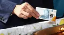 Gubernur Bank Inggris, Carney menunjukkan uang yang telah dicelupkan ke dalam kuah makanan, London, Selasa (13/9). Uang tersebut dikabarkan lebih tahan lama karena dicetak dengan menggunakan plastik film berbahan polimer. (REUTERS / Stefan Wermuth)