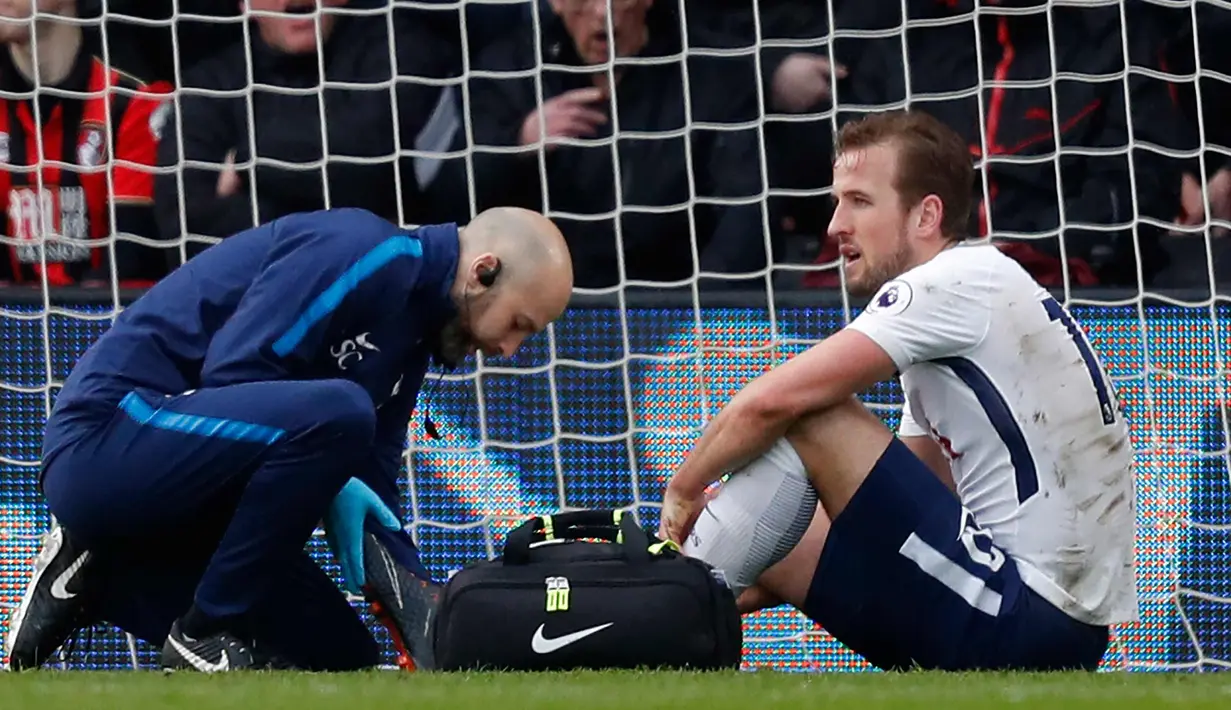 Penyerang Tottenham Hotspur, Harry Kane (kanan) mendapat perawatan tim medis setelah mengalami cedera saat melawan Bournemouth di Liga Inggris di Stadion Vitalitas di Bournemouth (11/3). Kane mengalami cedera pergelangan kaki. (AFP Photo/Adrian Dennis)