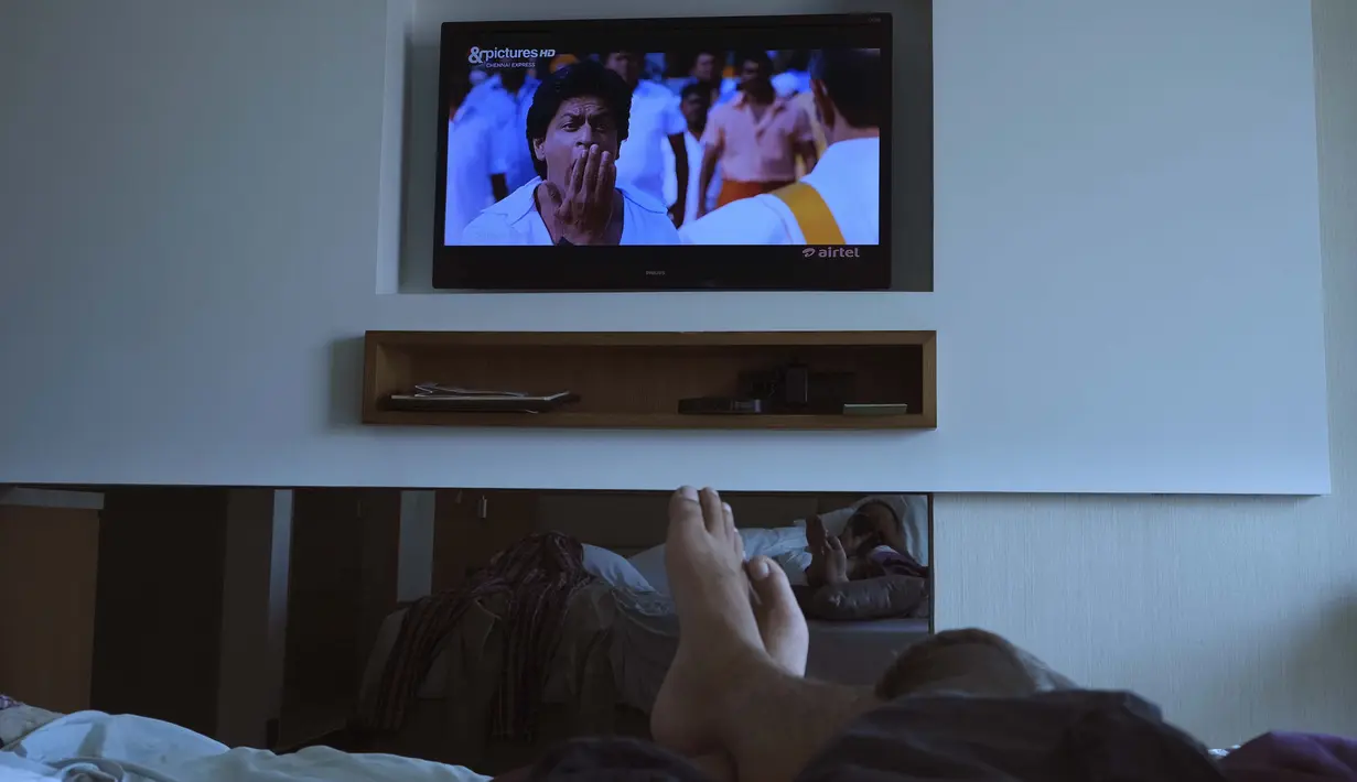 Fotografer Associated Press Rafiq Maqbool menonton film Bollywood dari televisi di sebuah kamar hotel tempat dia dikarantina, Mumbai, India, 23 April 2020. Selama beberapa hari berikutnya, kelompok WhatsApp bentukan penghuni hotel yang dikarantina menjadi keluarga barunya. (AP Photo/Rafiq Maqbool)