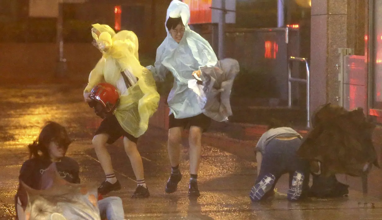 Sejumlah Warga terjatuh saat berjalan melawan angin Topan Soudelor mendekati wilayah Taipei, Taiwan, (7/8/2015). Ratusan warga dievakuasi dari rumah mereka karena topan terkuat dalam dua tahun terakhir mengancam wilayah tersebut. (REUTERS/Edward Lau)
