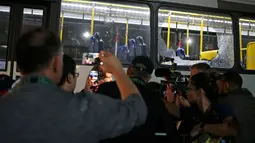 Seorang pria mengambil gambar kaca jendela bus pengangkut para jurnalis di Olimpiade Rio 2016 yang pecah ketika dalam perjalanan menuju pusat media centre di Barra da Tijuca, Selasa (9/8). Tak ada korban jiwa dalam insiden itu. (REUTERS/Adrees Latif)