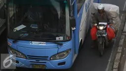 Pengendara motor membawa muatannya menggunakan jalur Trans-Jakarta di Jalan Otista Raya, Jakarta, Sabtu (19/11). Karena rendahnya separator jalan membuat pengendara dapat keluar masuk ke jalur busway. (Liputan6.com/Immanuel Antonius)