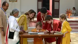 Perdana Menteri Kanada Justin Trudeau bersama keluarga melihat putra mereka Hadrien saat menandatangani sebuah buku pengunjung di Gandhi Ashram di Ahmedabad, India (19/2). (AFP Photo/Sam Panthaky)