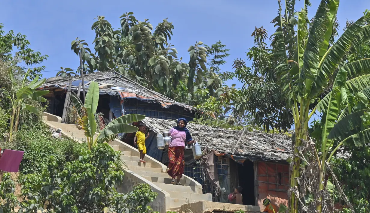 Pengungsi Rohingya kembali ke rumahnya setelah mengambil air di kamp pengungsi Jamtoli di Ukhia (22/3/2022). Ratusan ribu orang Rohingya melarikan diri dari Myanmar setelah tindakan keras tahun 2017, yang menjadi subjek kasus genosida di pengadilan tertinggi PBB di Den Haag. (AFP/Munir Uz Zaman)