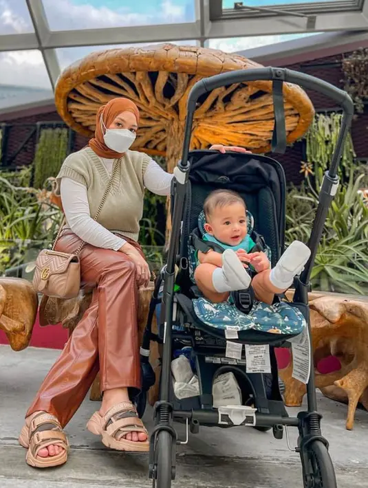 5. Kala berlibur ke Singapura, Nathalie tampil bergaya ala cewek bumi. Ia memadukan long sleeve putih, knit vest krem, leather pants coklat, dan hijab warna senada. (Instagram/nathalieholscher).