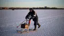Seorang pria usai memancing di laut Bothnia yang sedang membeku, Vaasa, Finlandia (29/12). Kebiasaan memancing di laut beku merupakan hal menantang yang ditunggu-tunggu oleh sebagian warga setempat. (AFP PHOTO/Olivier Morin)