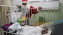Seorang pria berpakaian Sinterklas memberikan hadiah kepada seorang anak yang dirawat di rumah sakit di ruang gawat darurat sebuah rumah sakit di lingkungan El Cementerio di Caracas, Venezuela pada 25 Desember 2023. (Pedro Rances Mattey / AFP)