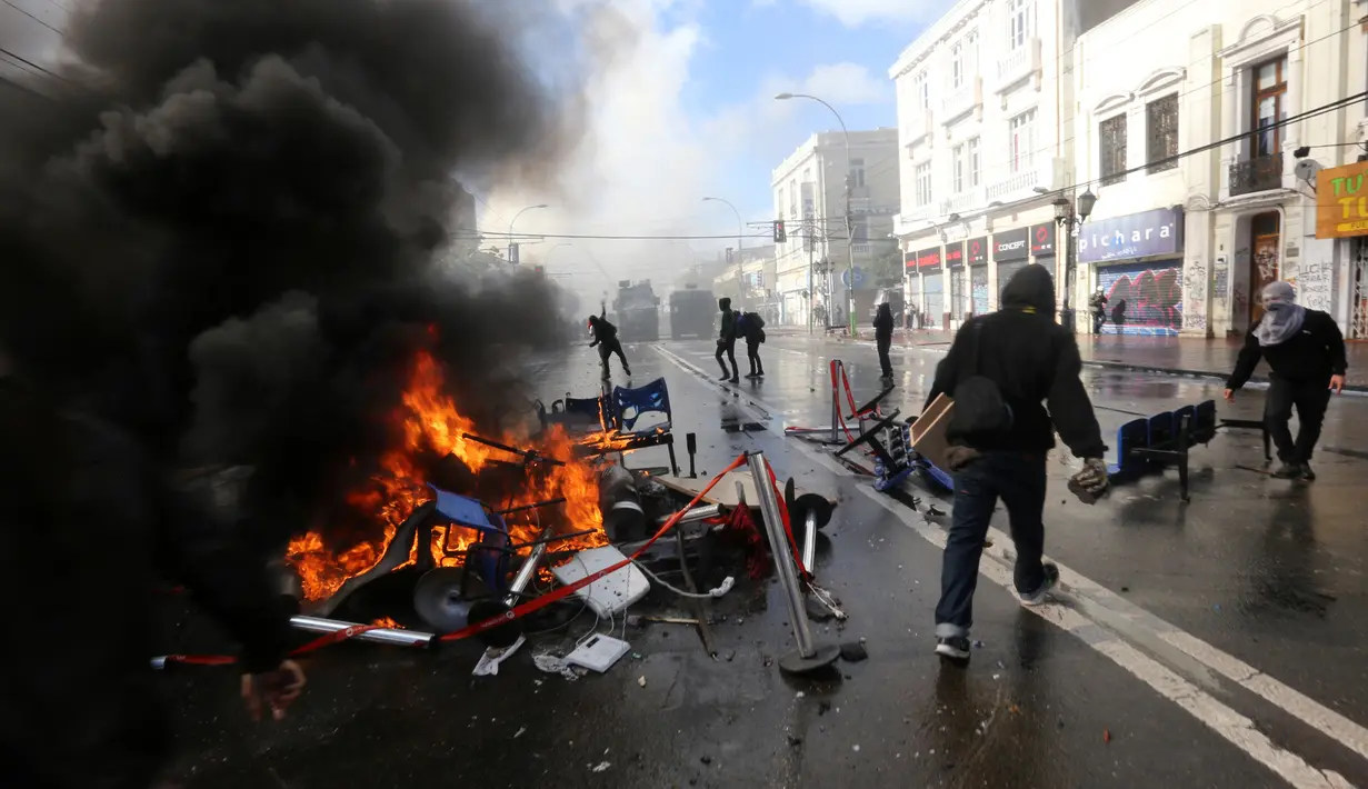 Demonstran membakar sejumlah barang saat unjuk rasa yang berakhir ricuh di sekitar Kongres di Valparaiso, Chili. Sabtu (21/5). Peristiwa itu menyebabkan sejumlah gedung terbakar dan seorang polisi tewas. (AFP Photo/Claudio Reyes)