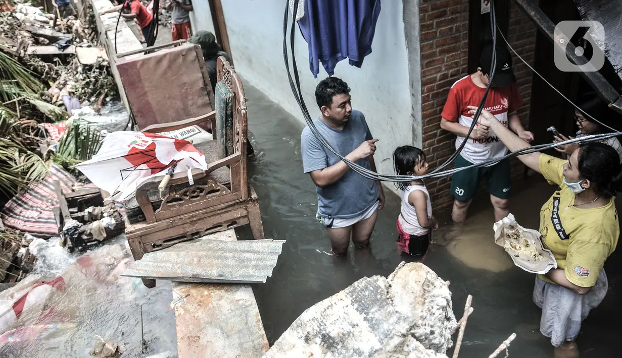 Warga beraktivitas di tengah banjir yang merendam permukiman warga di Kemang Timur XI, Jakarta, Minggu (21/2/2021). Longsor yang merusak rumah dan menutup aliran kali membuat RT 10 dan 12, RW 03, Kelurahan Bangka, Kecamatan Mampang Prapatan masih terendam banjir. (merdeka.com/Iqbal S. Nugroho)