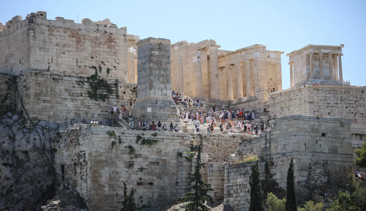 Wisatawan meninggalkan kuil kuno Parthenon di bukit Acropolis di Athena, Yunani pada Rabu (17/7/2024). (Aris Oikonomou / AFP)
