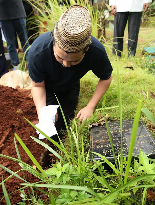 Namun ia tetap berdiri tegar memberikan penghormatan terakhir untuk anaknya. Sebagai ayah, ia juga menjadi orang yang pertama kali menaburkan bunga di atas pusara Athar. (Bambang E. Ros/Bintang.com)