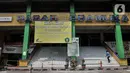 Pekerja berjalan di dekat spanduk info penutupan di Pasar Pramuka, Jakarta, Minggu (12/7/2020). Kegiatan jual beli di Pasar Pramuka ditiadakan selama tiga hari, mulai Sabtu (11/7) hingga Senin (13/7) setelah satu orang pedagang terkonfirmasi positif Covid-19. (merdeka.com/Iqbal Nugroho)