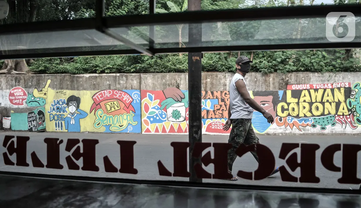 Warga melintasi mural bertema imbauan protokol kesehatan COVID-19 di kawasan Cakung Barat, Jakarta, Minggu (18/10/2020). Mural karya warga setempat tersebut bertujuan mengingatkan masyarakat akan pentingnya memakai masker, menjaga jarak, dan mencuci tangan. (merdeka.com/Iqbal S. Nugroho)
