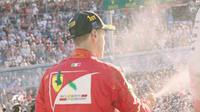 Pebalap Ferrari, Sebastian Vettel, menyemprotkan sampanye di podium setelah menjuarai balapan F1 GP Australia di Albert Park, Melbourne, Minggu (26/3/2017). (Bola.com/Twitter/F1)