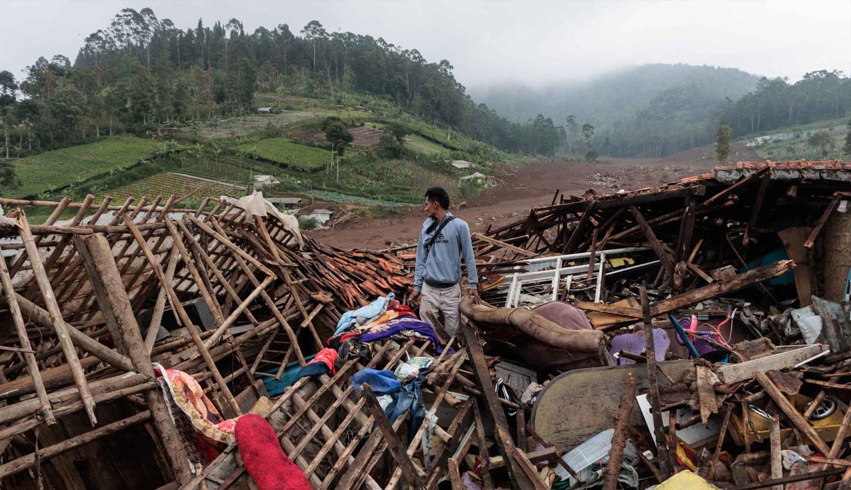 Seorang pria berdiri di dekat reruntuhan rumah saat tim penyelamat mencari korban yang terkubur longsor di Desa Pasirlangu, Cisarua, Kabupaten Bandung, Jawa Barat, pada 26 Januari 2026. Hari ini Selasa 27 Januari 2026, operasi pencarian dan pertolongan korban longsor di Desa Pasirlangu, Cisarua, Kabupaten Bandung, Jawa Barat, kembali dilanjutkan. (Aditya Aji/AFP)