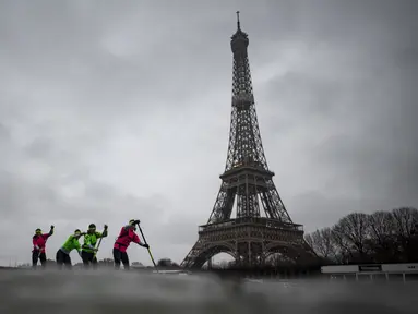 Para peserta Nautic Paddle Race atau lomba dayung sambil berdiri melintas dekat Menara Eiffel di Sungai Seine, Paris, Minggu (8/12/2019). Sekitar 1000 pesaing ikut serta dalam lomba sejauh 11 kilometer menyeberangi sungai Seine dengan pemandangan kota Paris. (Photo by Olivier MORIN / AFP)