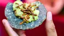 Seseorang memakan tortilla jagung dengan cacing dan guacamole di sebuah pasar di Mexico City, Meksiko, Minggu (10/6). (Ronaldo SCHEMIDT/AFP)