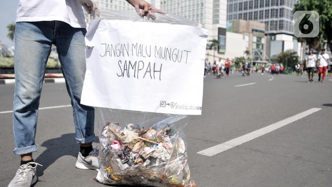 Aktivis yang tergabung dalam Sekolah Relawan memunguti sampah saat aksi Jakarta Clean Action selama Hari Bebas Kendaraan Bermotor (HBKB) di kawasan Bundaran HI, Jakarta, Minggu (1/12/2019). (merdeka.com/Iqbal S. Nugroho)