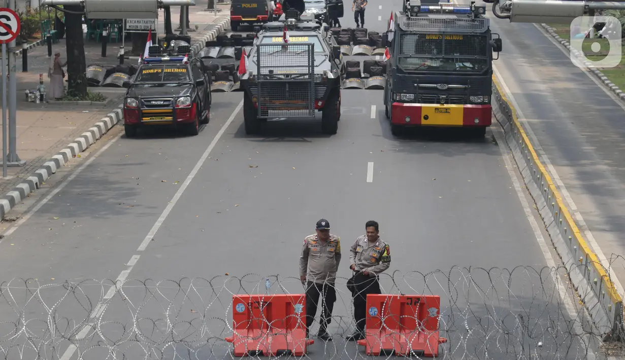Personel Kepolisian berjaga dibalik barikade kawat berduri yang menutup ruas Jalan Medan Merdeka Barat, Jakarta, Senin (28/10/2019). Penutupan ini antisipasi aksi unjuk rasa mahasiswa mendesak Presiden Jokowi segera mengeluarkan Perppu KPK. (Liputan6.com/Helmi Fithriansyah)