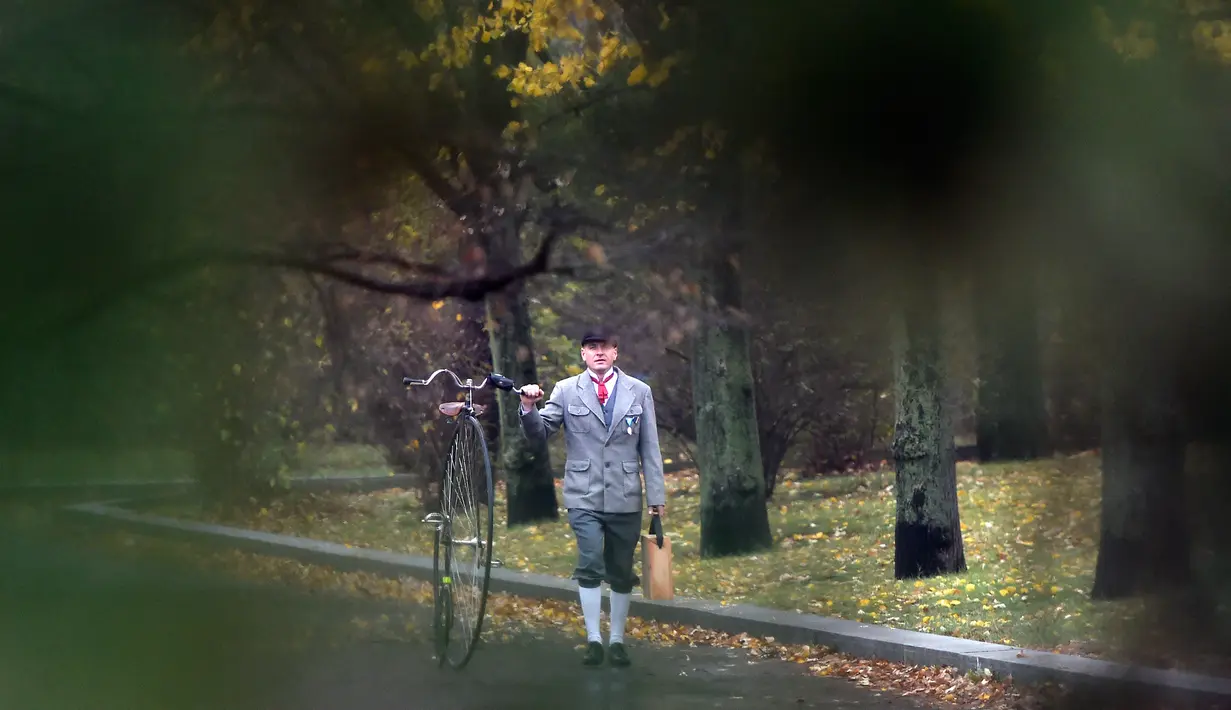 Seorang penggemar sepeda mengenakan kostum sejarah sambil menuntun Penny Farthing atau dikenal sebagai sepeda roda tinggi selama kompetisi tradisonal 'One Mile Race' di Praha, Republik Ceko pada 3 November 2018. (Photo by Michal CIZEK / AFP)