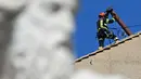 Seorang pekerja memasang cerobong asap di atap Kapel Sistina, Vatikan, pada 2 Mei 2025. (Gabriel BOUYS/AFP)