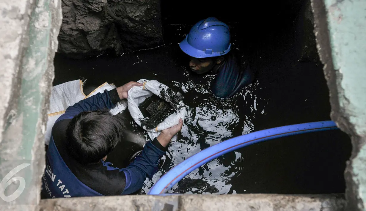 Petugas harian lepas (PHL) Sudin SDA membersihkan endapan pasir dan sampah dalam gorong-gorong di Jalan Gatot Subroto, Jakarta, Jumat (10/3). Pembersihan dilakukan karena di kawasan ini banjir selalu datang saat hujan turun. (Liputan6.com/Yoppy Renato)