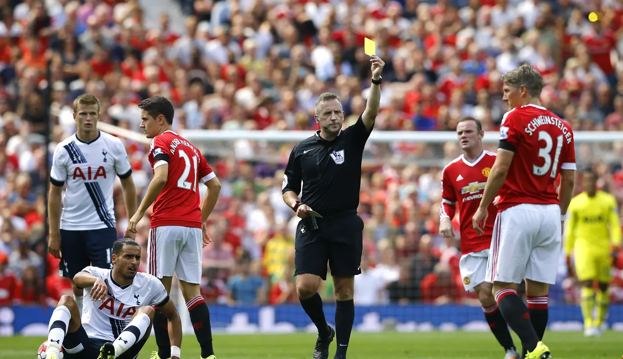 Pemain MU, Bastian Schweinsteiger (kanan) mendapat kartu kuning dari wasit Jonathan Moss setelah menjatuhkan pemain Spurs dalam pertandingan di Stadion Old Trafford, Inggris. Sabtu (8/8/205). (Action Images via Reuters/Darren Staples)
