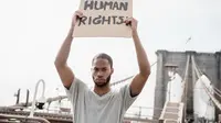 Ilustrasi HAM/ Hak Asasi Manusia (Photo by Lara Jameson: https://www.pexels.com/photo/man-in-a-gray-shirt-holding-a-human-rights-sign-8898590/)