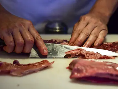 Seorang koki menyiapkan potongan daging untuk dimasak di dapur restoran Don Julio di lingkungan Palermo, Buenos Aires, Argentina, Kamis (20/5/2021). Pemerintah Argentina memutuskan untuk menghentikan ekspor daging sapi selama satu bulan lamanya. (RONALDO SCHEMIDT/AFP)