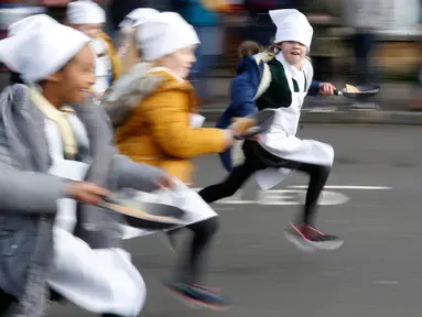 Anak-anak sekolah-sekolah lokal mengambil bagian dalam lomba lari sembari membawa wajan berisi pancake di Olney, Buckinghamshire, Inggris, Selasa (25/2/2020). Peserta kompetisi yang sudah ada sejak tahun 1445 ini harus membolak-balikan pancake sambil tetap berlari. (AP/Alastair Grant)