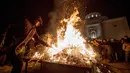 Seorang pria membakar ranting pohon oak kering  atau Yule log selama perayaan Hari Natal Ortodoks di Belgrade, Serbia (6/1). Umat Kristen Ortodoks di Serbia memiliki tradisi yang cukup unik dalam merayakan Natal, yaitu membakar ranting. (AFP/Oliver Bunic)