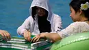 Seorang wanita dan temannya bermain mahjong di dalam kolam renang di Chongqing, Tiongkok, Rabu (2/8). Pemerintah setempat telah mengeluarkan peringatan merah terkait cuaca panas dengan suhu di beberapa daerah hampir mencapai 40 derajat celcius (STR / AFP)