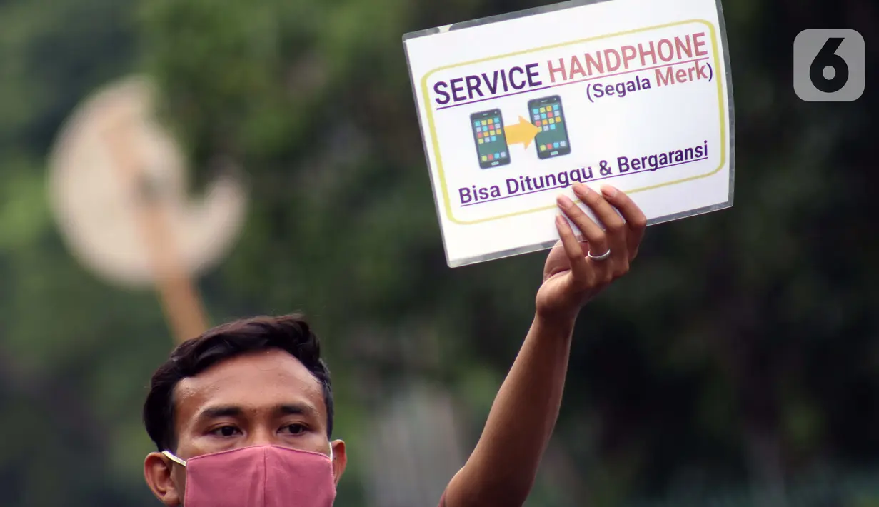 Penjual jasa perbaikan telepon genggam menawarkan jasanya di depan Mall Pusat Grosir Cililitan, Jakarta, Kamis (14/5/2020). Sejak pemberlakuan Pembatasan Sosial Berskala Besar yang berimbas pada penutupan pusat-pusat perbelanjaan, pendapatan mereka turun drastis. (Liputan6.com/Helmi Fithriansyah)
