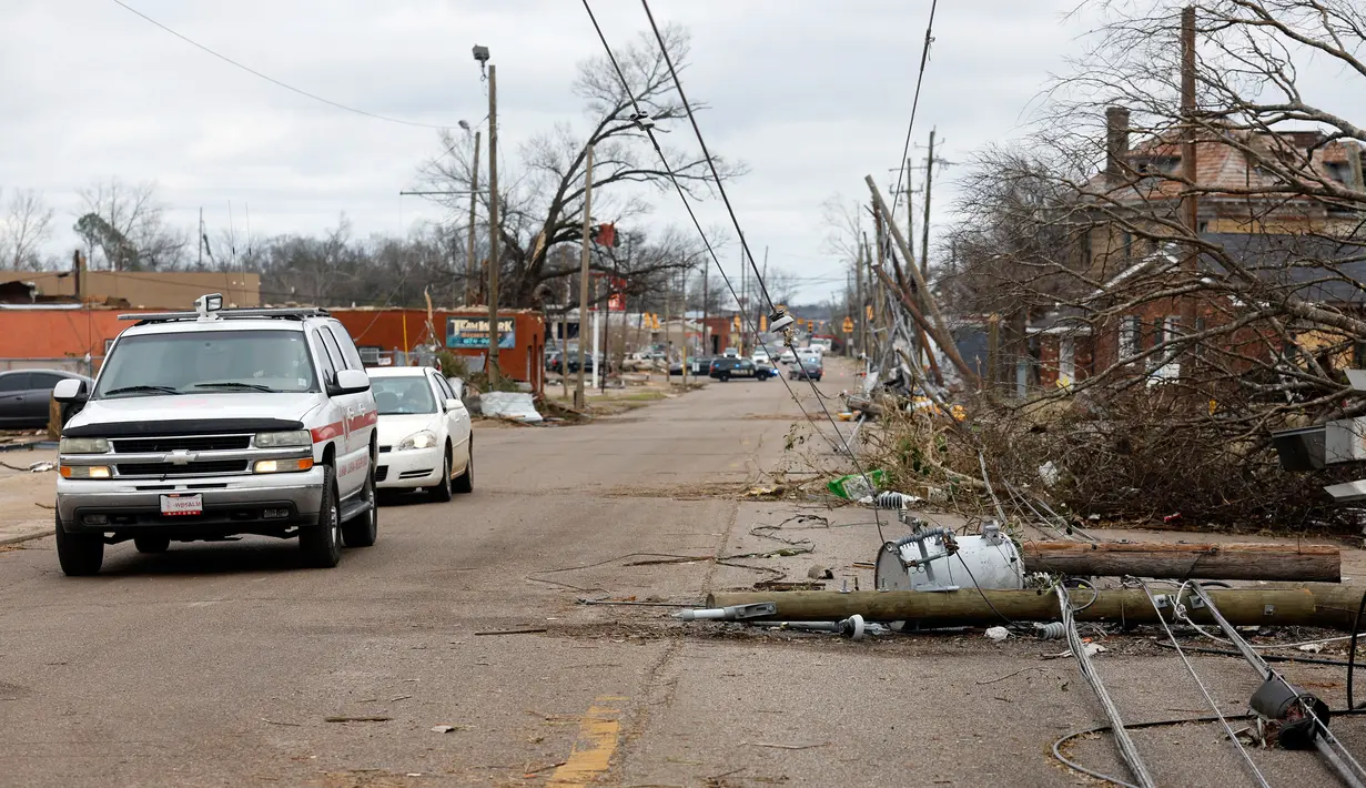 Mobil melewati pepohonan dan kabel listrik yang tumbang setelah tornado di Chestnut Blvd, Selma, Alabama, Amerika Serikat, 13 Januari 2023. Semua kematian akibat tornado yang dilaporkan di Alabama terjadi di Autauga County, yang terletak di antara Kota Montgomery dan Selma. (AP Photo/Stew Milne)