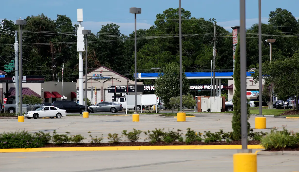 Aparat penegak hukum berkumpul di lokasi penembakan petugas kepolisian di Baton Rouge, Louisiana, AS, Minggu (17/7). Insiden terjadi setelah seorang pria bersenjata, bertopeng dan berpakaian hitam melepas tembakan dengan senapan serbu (REUTERS/Joe Penney)