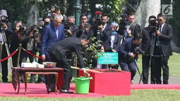 Presiden Joko Widodo (Jokowi) bersama PM Malaysia, Mahathir Mohamad menyiram pohon yang baru mereka tanam di halaman belakang Istana Bogor, Jumat (29/6). Penanaman pohon Meranti itu dalam rangkaian penyambutan PM Mahathir. (Liputan6.com/Angga Yuniar)