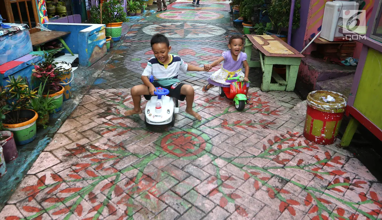 Anak-anak bermain sepeda dengan lantai warna-warni cat dinding dan grafiti di Kampung Bekelir, Babakan Kota Tangerang, Jumat (16/11). Sebanyak 120 seniman mural dilibatkan untuk mengecat rumah. (Liputan6.com/Fery Pradolo)